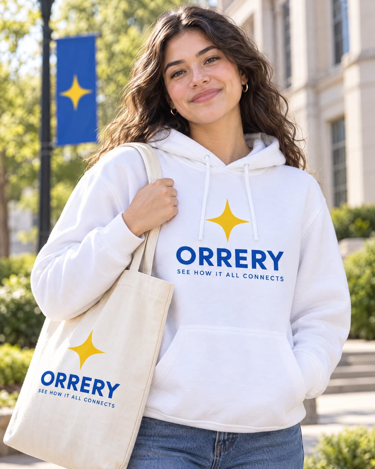 A student outdoors in a branded hoodie carrying a matching canvas tote on a campus