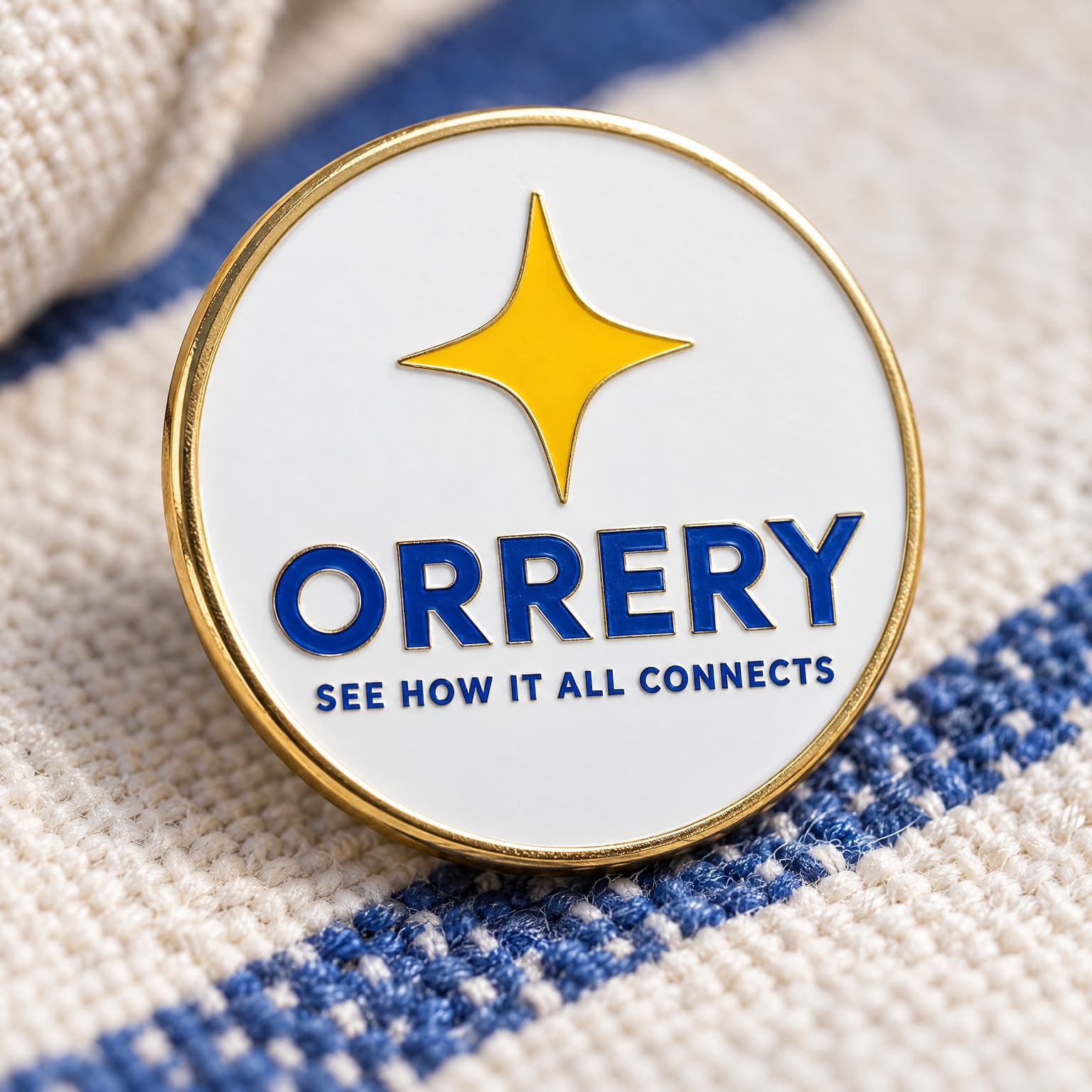 A macro photograph of a branded enamel pin resting on woven fabric